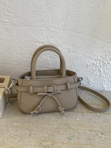 Khaki crossbody mini handbag with star pendants and bow detail on stone background
