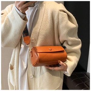 Dettaglio borsa a cilindro arancione vintage con ampia tracolla a fantasia alla moda