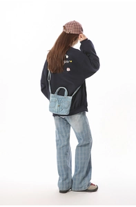 Back view of a light blue denim crossbody bag featuring jeans-style pocket details