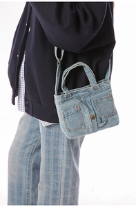 Detailed macro view of light blue denim bag with Jean pocket style and metal button