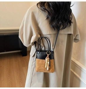 Detail of suede bucket bag with diamond stitching and decorative wooden beads