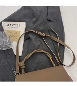 Detail of brown litchi pattern leather bag with knotted handle and matte gold hardware