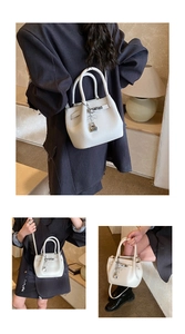 Detailansicht der beigen Eimer-Handtasche aus genarbtem Leder mit silbernem Herzschloss