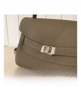 Close-up of taupe litchi grain leather texture and silver metal twist lock detail