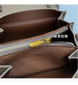 Detail view of smooth golden zipper and multi-compartment interior of the handbag