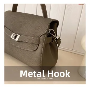 Detail of silver hardware hook and white stitching on grey lychee grain leather bag