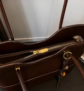 Close-up of smooth gold zipper and hardware on vintage dark brown leather tote bag