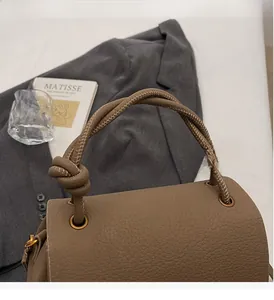 Detail of dark brown lychee grain leather handbag with knotted handle and bronze ring