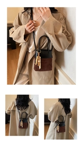 Detail of a bicolored suede bucket bag with wooden bead tassel and crossbody strap