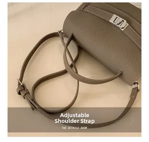 Close-up of adjustable strap and silver turn-lock on grey lychee leather crossbody bag