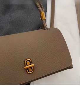 Detail of dark coffee flap crossbody bag featuring lychee grain leather and gold metal lock