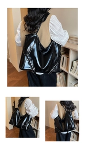 Détail du sac cabas en cuir noir brillant avec boucle métallique et lanières sur le côté