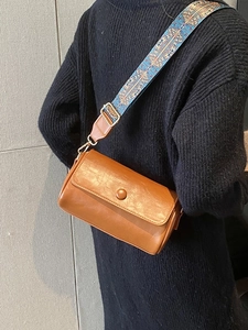Borsa a tracolla in pelle marrone con ampia tracolla etnica blu indossata dal modello