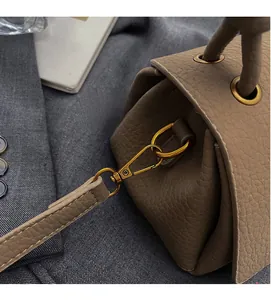 Detail of high-gloss gold metal hooks and pebble grain leather texture on a tote bag