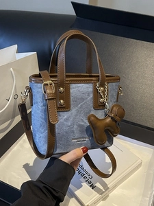 Borsa a secchiello in denim blu e pelle marrone con manico e ciondolo a cavallo