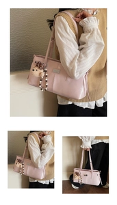 Pink tote bag detail with plush bear charm and beaded chain on matte leather finish