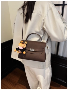 Detail of a dark brown lychee leather handbag with a silver turn-lock and dog charm