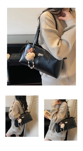 Detail view of a black faux leather shoulder bag with a cute bear pendant and silver tag