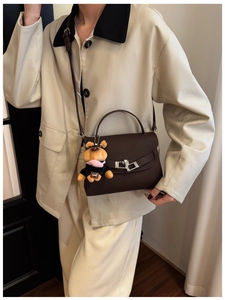 Detail of coffee brown pebble leather handbag with silver lock and sweet dog charm