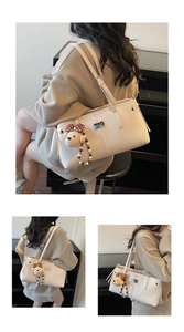 Detail of a large off-white tote bag featuring a cute brown plush bear charm accessory