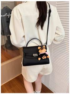 Detail of black pebbled leather handbag featuring a silver twist lock and cute dog charm