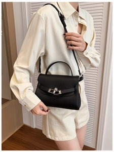 Detail of black lychee grain leather mini bag with silver buckle on a stylish model