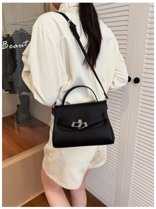 Close-up of black litchi pattern leather handbag with silver metal rotating lock buckle