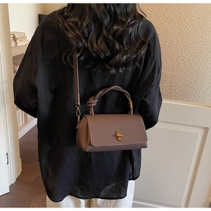 Brown litchi grain leather handbag with knot handle and gold hardware on model