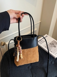 Chic two-tone bucket bag with black leather and brown quilted suede held by hand