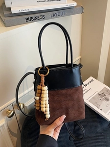 Quilted bucket bag in black and brown suede with a decorative wooden bead tassel