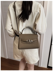 Rear view of model wearing a pebble leather trapezoid bag with silver twist lock