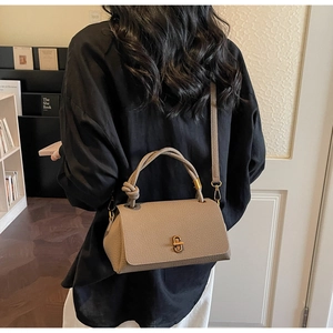 Close-up of khaki pebbled leather handbag with knotted handle and gold metal twist lock