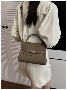 Model wearing a gray lychee grain leather handbag showing scale and trapezoid structure