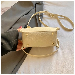 Close-up of cream leather pillow bag bottom with four protective gold metal studs