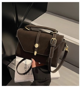 Close-up of vintage dark brown faux leather bag with white stitching and gold hardware