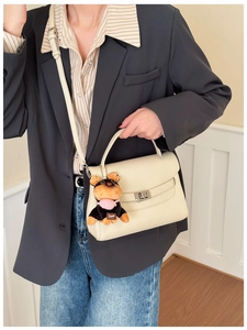Detail of cream white leather mini bag with metal lock and cute dog charm on side