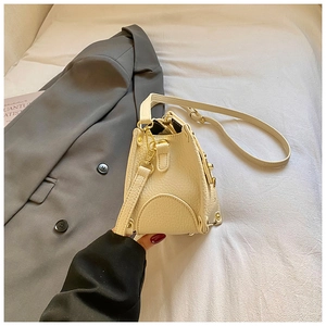 Detail shot of cream leather crossbody bag with lychee texture and gold metal buckle