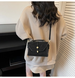 Detail of vintage black suede handbag with white stitching and gold metal ring lock