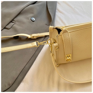 Close-up of cream lychee texture leather handbag with gold metal clasp and zipper details