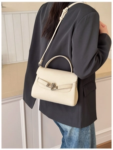 Detail of off-white lychee pattern leather texture and silver buckle on crossbody bag