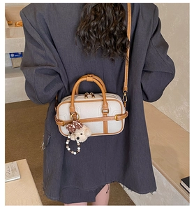 Détail du sac en cuir texturé avec breloque d'ours et bandoulière marron