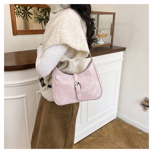 Close-up of a pink faux leather underarm bag with silver buckle worn by a model