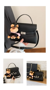 Detail view of black lychee grain leather bag with silver lock and cute puppy charm
