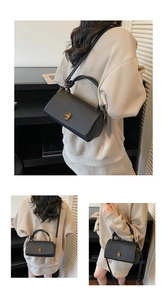 Detail of black pebbled leather crossbody bag with golden twist lock and knot handle design