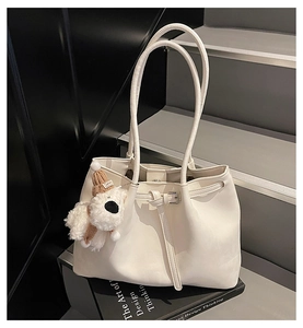 Gros plan d'un sac cabas blanc en similicuir avec un charmant pendentif chiot