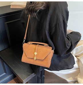 Caramel brown vintage crossbody bag with gold buckle on a model in a casual setting