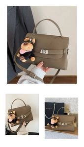 Detail view of khaki textured leather handbag with a plush puppy charm and metal lock