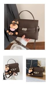 Detailed view of dark brown pebbled leather handbag with silver clasp and plush dog charm