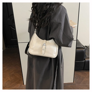 Detail of cream hobo bag with silver metallic buckle and glossy leather texture
