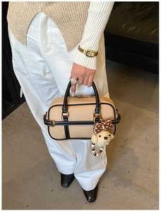 Détail du sac en cuir texturé beige avec bordure noire et pendentif chien peluche
